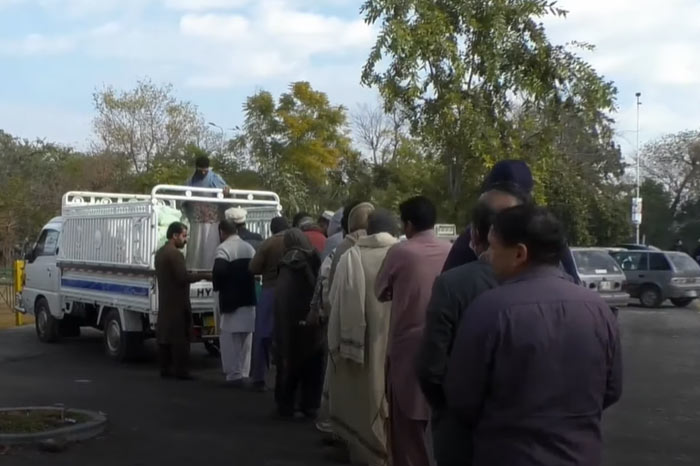Pakistani people queue to buy wheat flour