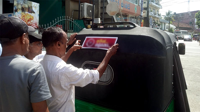 Sticking stickers promoting presidential candidates on vehicles in Sri Lanka