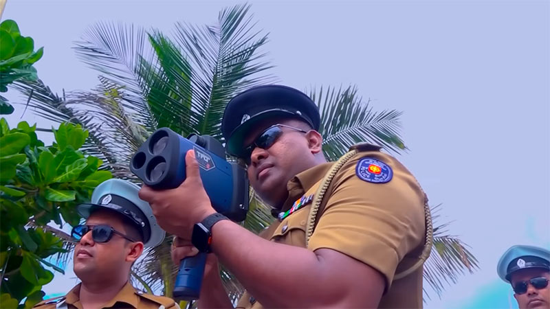 A Sri Lanka Police officer operating a speed gun to monitor vehicle speeds